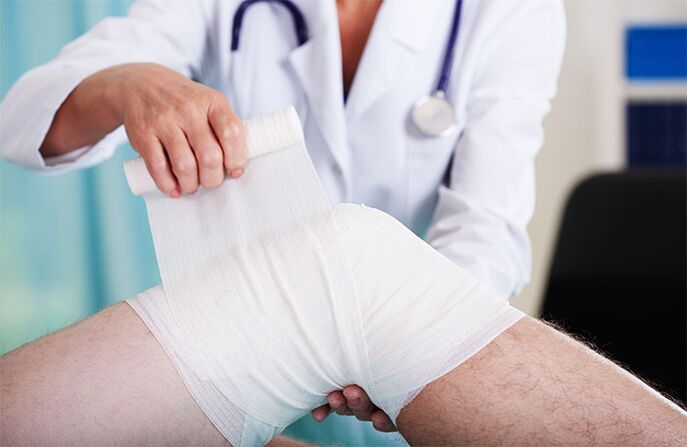 doctor bandaging the knee joint with arthropathy
